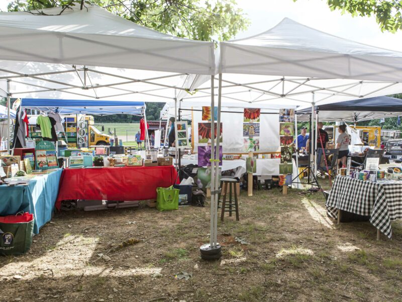 Events at a farm showing tents and tables selling books and flower photo art.